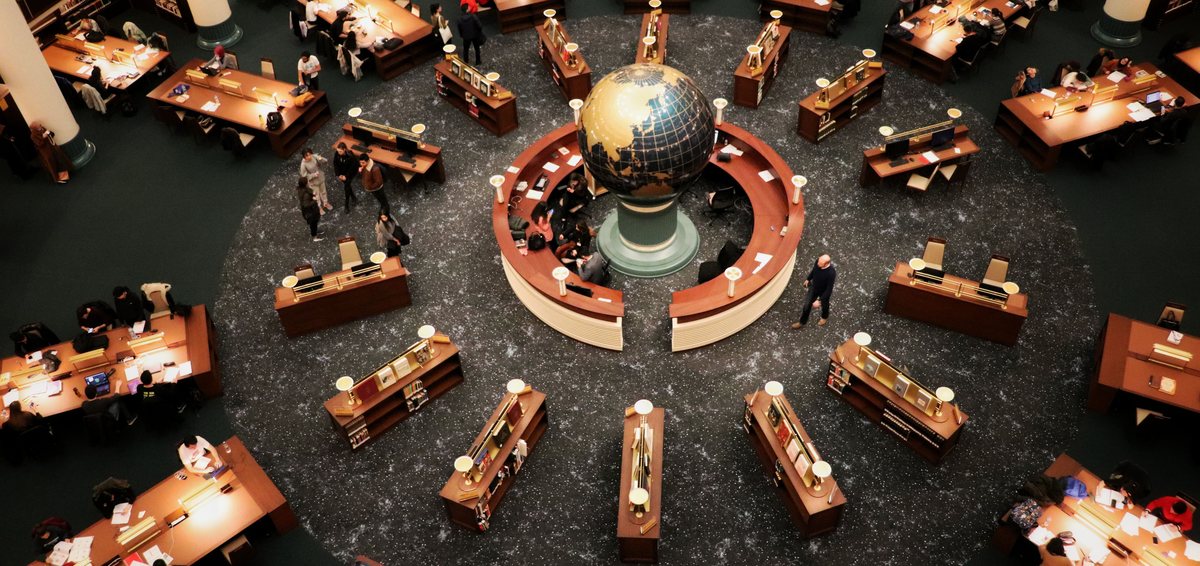 A library reading room with desks arranged around a globe