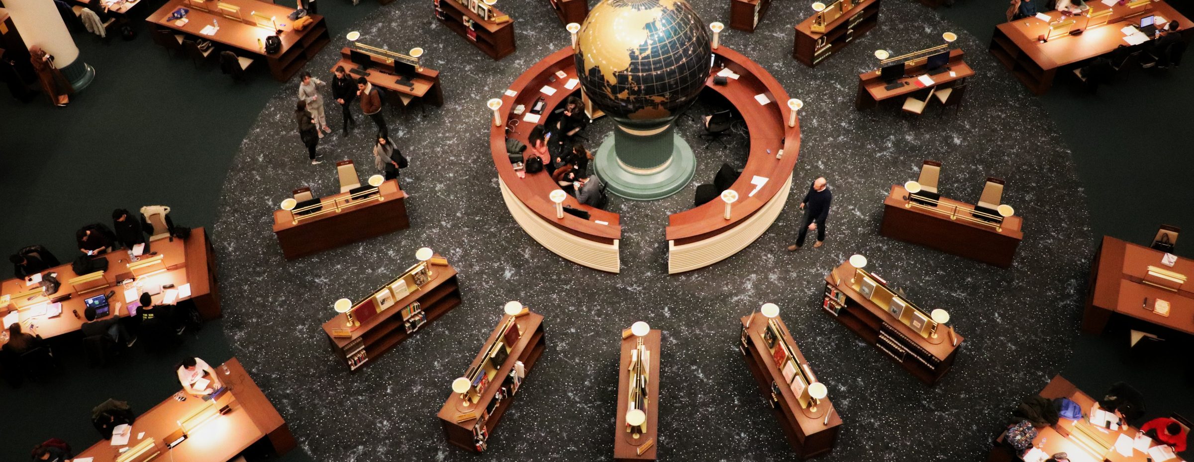 A library reading room with desks arranged around a globe